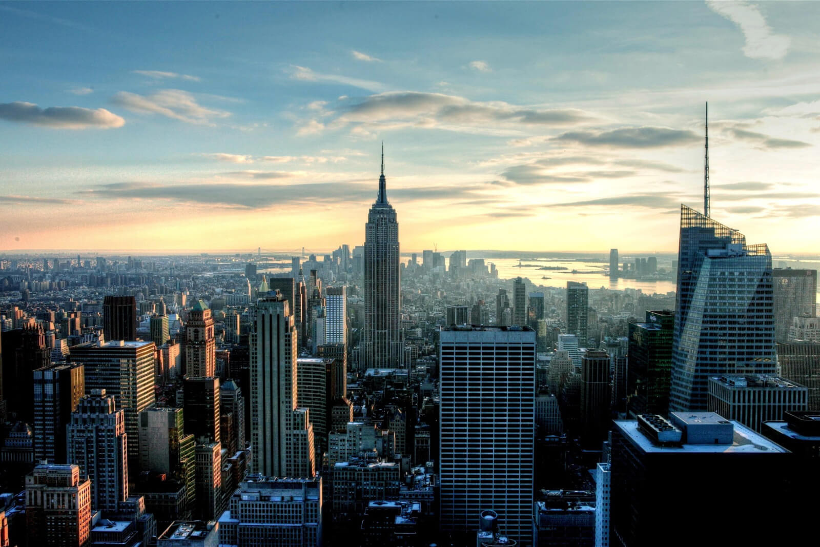 Aerial city skyline at sunset with tall skyscrapers and hazy golden light, blue and orange tones